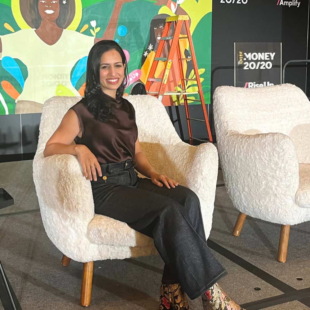 Farah Hussain sitting in a white chair on a stage